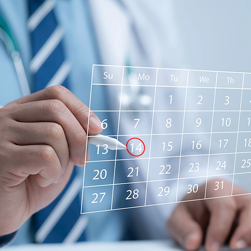 A close-up of a person in a professional white shirt and blue striped tie using a stylus to circle the 14th on a digital, transparent calendar overlay. The image represents scheduling an appointment or a project deadline.